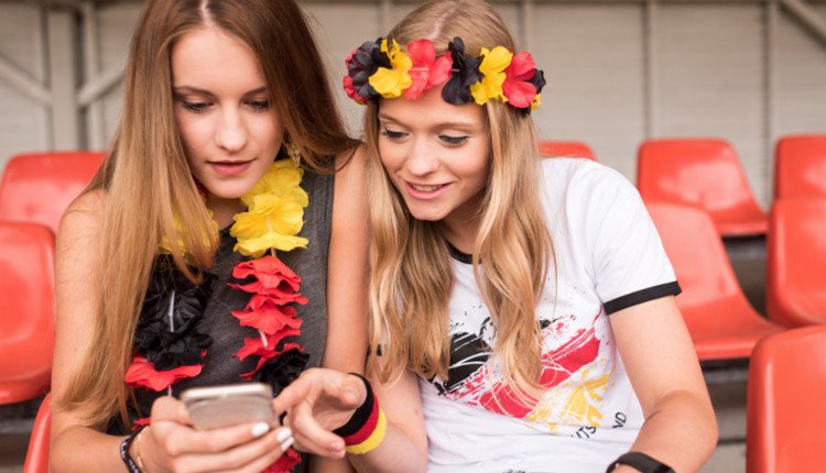 Mädchen schauen im Deutschland-Look auf ihr Smartphone