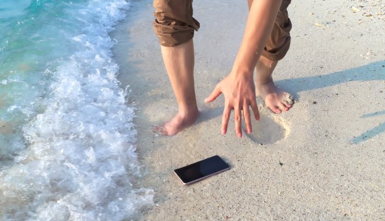 Handy fällt am Strand in den Sand