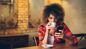 Frau mit Kaffee und Smartphone