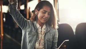 Junge Frau mit In-Ear-Kopfhörer im Bus