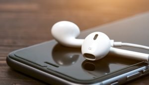 Weiße In-Ear-Kopfhörer liegend auf iPhone-Display