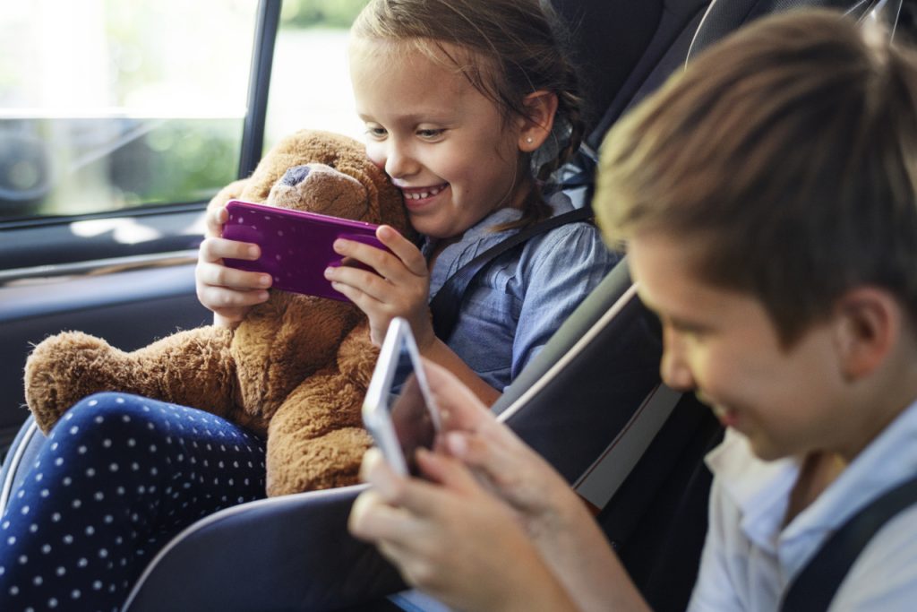 Glückliche Kinder nutzen Smartphone im Auto